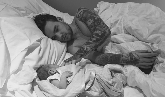 Liam Payne lying shirtless on a bed with his newborn son Bear