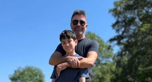 Eric and Simon Cowell playing with a dog in a park